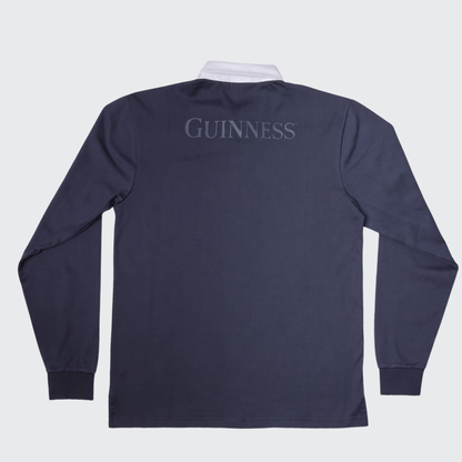 The Guinness Navy Traditional Rugby Jersey from Guinness Webstore US features a navy long-sleeve design with a white collar in a classic rugby style, and “GUINNESS” printed in gray on the upper back.