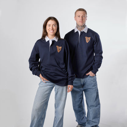 Two people wearing Guinness Navy Traditional Rugby Jerseys from the Guinness Webstore US—with white collars—pair their tops with jeans as they stand side by side against a plain white background.