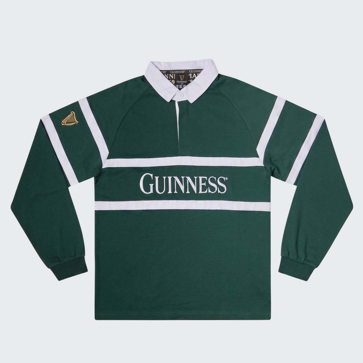 Guinness Green Traditional Rugby Jersey by Guinness features long sleeves, classic white stripes and collar, and a “Guinness” logo across the chest. A gold harp emblem on the sleeve adds an authentic Irish rugby touch.