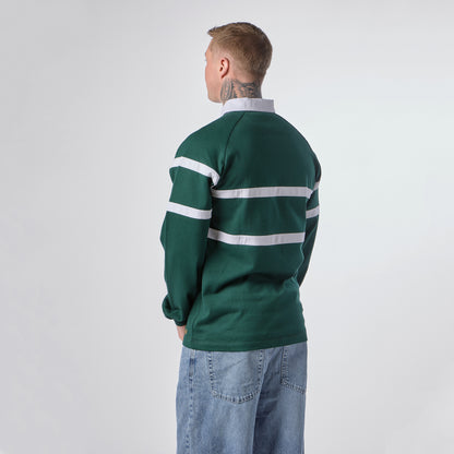 A person with short hair, wearing the Guinness Green Traditional Rugby Jersey by Guinness and blue jeans, is standing with their back to the camera against a plain background.