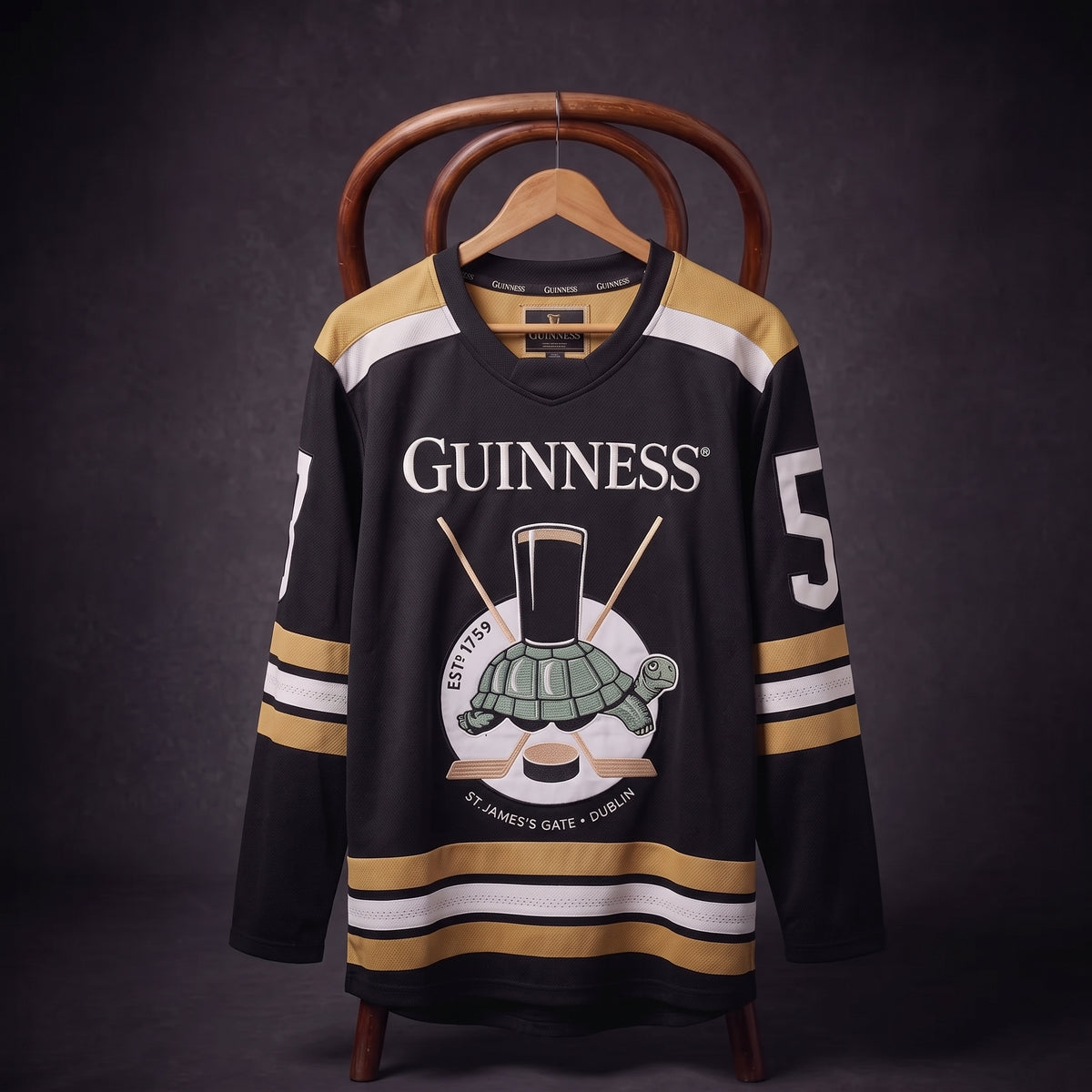The Guinness Tortoise Hockey Jersey by Guinness Webstore US is displayed on a hanger against a dark background, featuring black and gold colors, the iconic “Guinness” logo, a pint glass, turtle illustration, and the number 5 on the sleeve. Expertly crafted from recycled polyester hockey jersey material.
