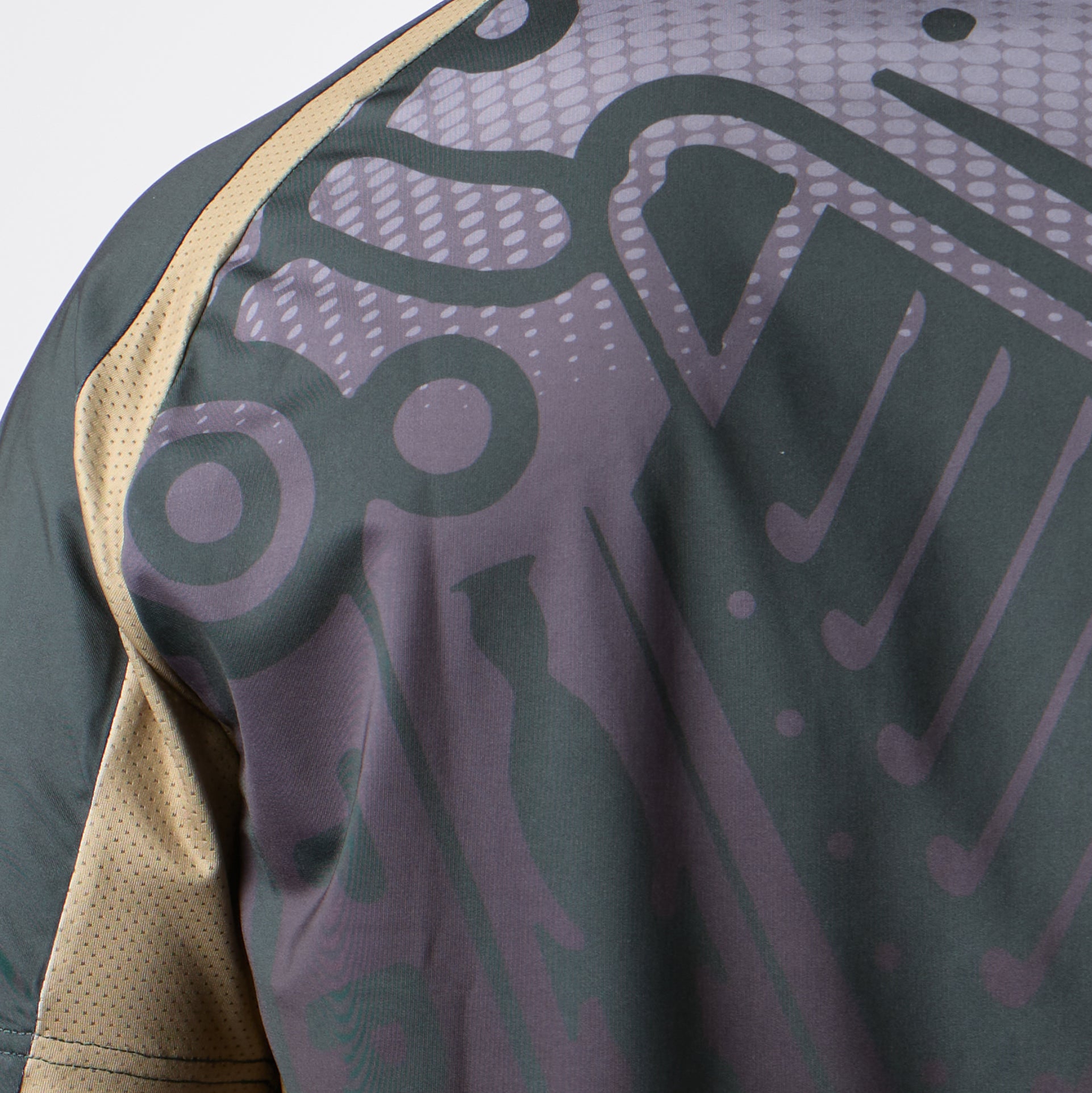 Close-up of the Guinness Retro Harp Performance Soccer Jersey by Guinness, showcasing a dark abstract pattern with geometric and curved shapes in varying shades of gray and purple, complemented by a beige mesh sleeve. The design nods to classic performance soccer jerseys and echoes the iconic style of vintage Guinness sportswear.