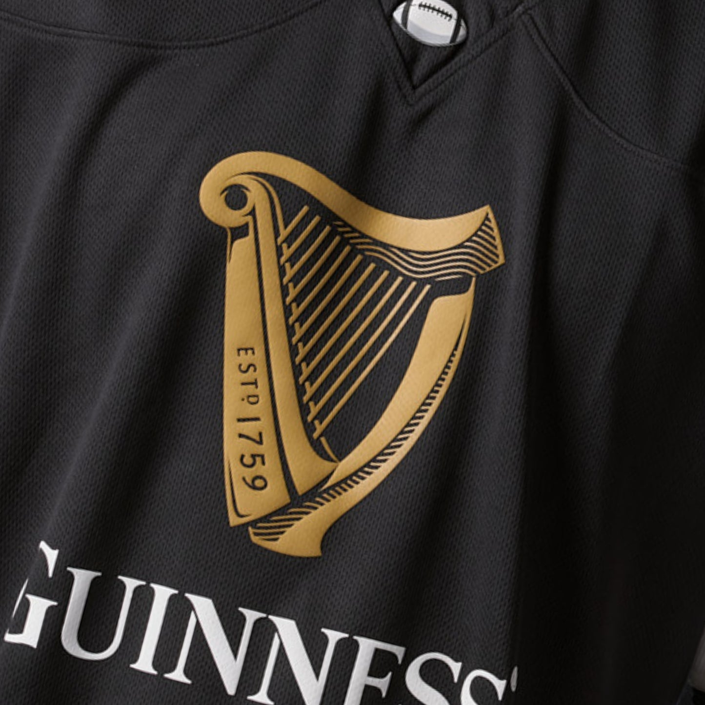 The Guinness Black American Football Jersey from the Guinness Webstore US features a gold harp design labeled “ESTD 1759” and the partial word “GUINNESS” in white letters below the harp.
