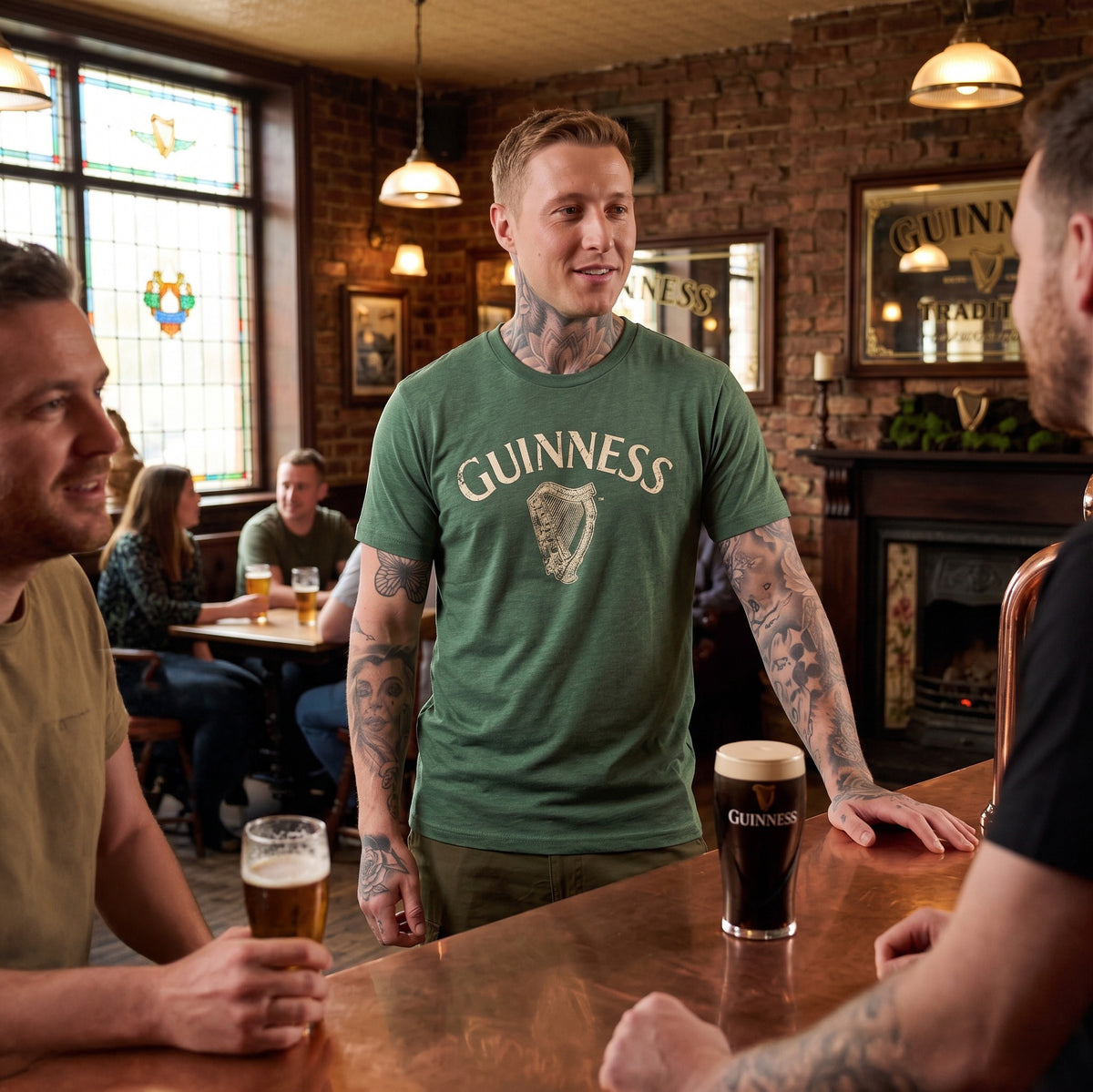 Three men converse at a pub bar over drinks, while two other patrons sit in the background. Guinness branding appears on shirts—including a graphic tee styled as the Guinness Vintage Harp Tee—as well as on glasses and wall signs.