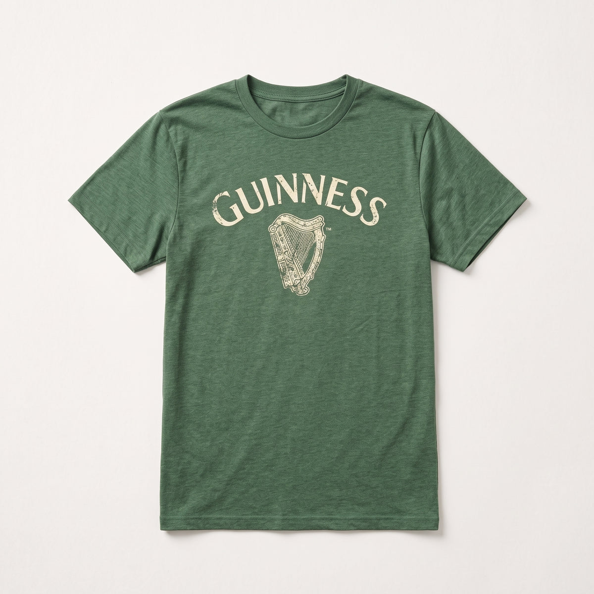 The Guinness Vintage Harp Tee is a green unisex short-sleeve t-shirt featuring the “Guinness” name and a vintage white harp logo printed on the chest, shown laid flat on a white background. This classic piece combines iconic Guinness branding with timeless style.