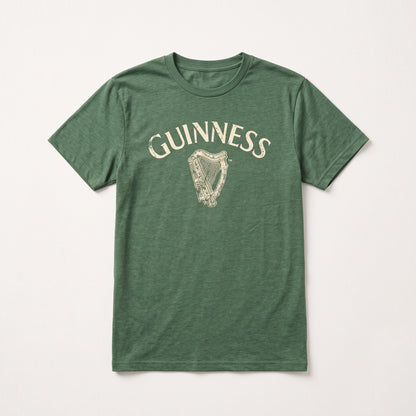 The Guinness Vintage Harp Tee is a green unisex short-sleeve t-shirt featuring the “Guinness” name and a vintage white harp logo printed on the chest, shown laid flat on a white background. This classic piece combines iconic Guinness branding with timeless style.