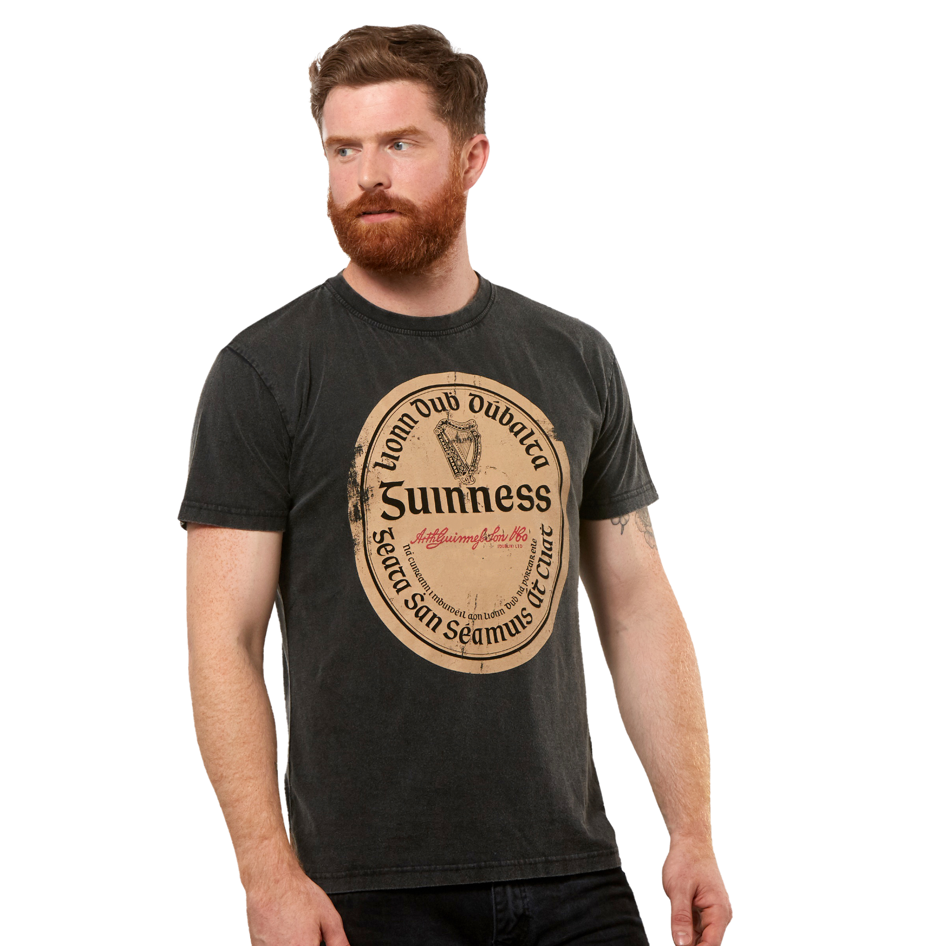 A man with a red beard wears the Guinness Black Distressed Label Tee, a unisex shirt featuring a large vintage-style graphic on the front.