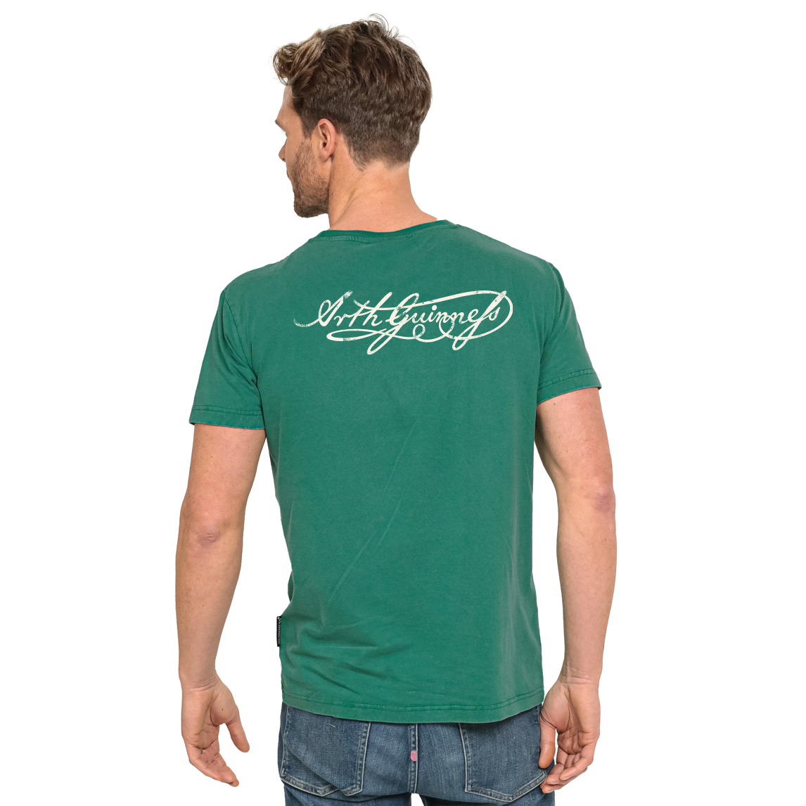 A person wearing a Guinness Green Label Premium Tee, which is green with white cursive script across the back shoulders.