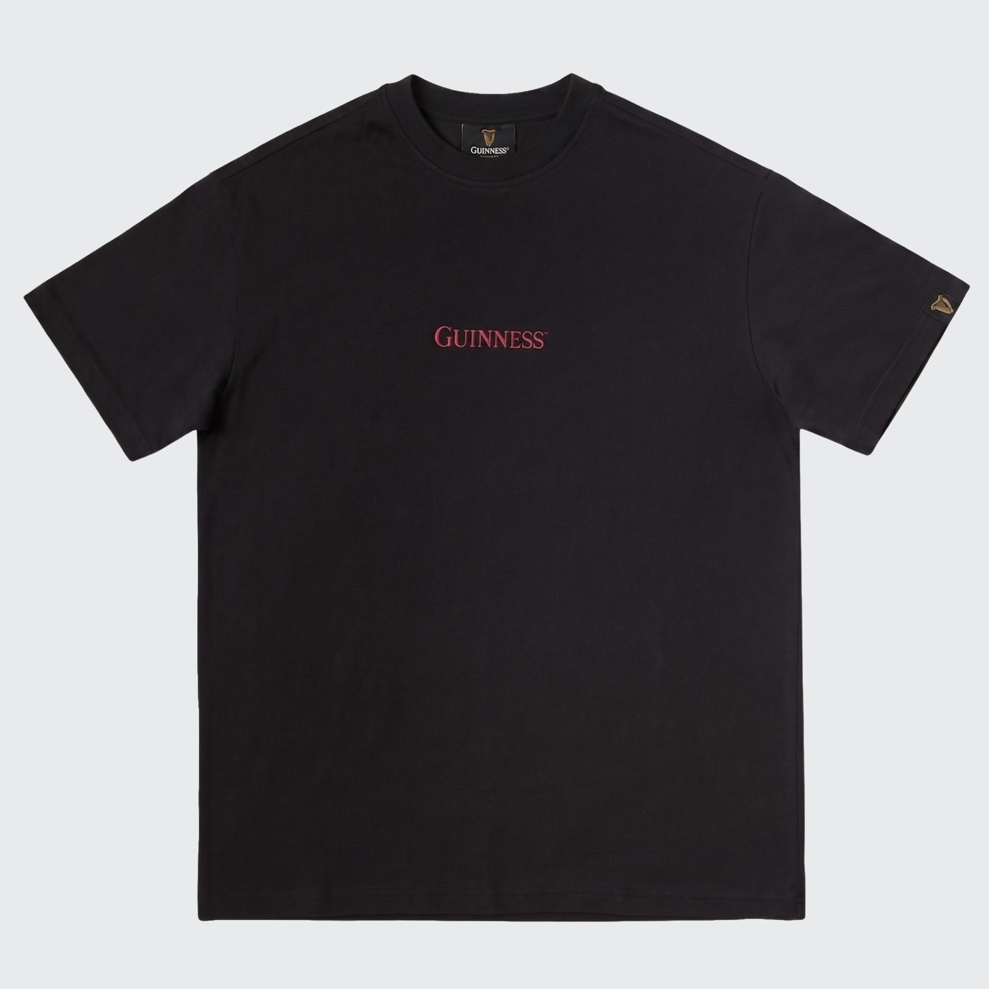 Introducing the Guinness Gilroy Ostrich Tee – Black from Guinness Webstore US: a black short-sleeve t-shirt showcasing bold red “Guinness” text centered on the chest and a small gold harp logo on the left sleeve, inspired by the Iconic Gilroy collection. This limited edition tee is an ideal choice for fans seeking classic style with a distinctive twist.