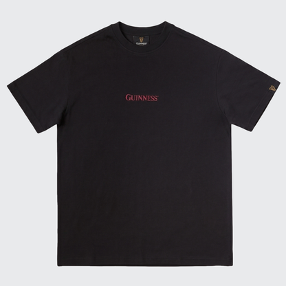 Introducing the Guinness Gilroy Ostrich Tee – Black from Guinness Webstore US: a black short-sleeve t-shirt showcasing bold red “Guinness” text centered on the chest and a small gold harp logo on the left sleeve, inspired by the Iconic Gilroy collection. This limited edition tee is an ideal choice for fans seeking classic style with a distinctive twist.