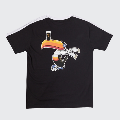 The Guinness Toucan Soccer Black Tee from Guinness Webstore US showcases a vibrant graphic of a toucan balancing a pint of “Guinness” on its beak while holding a banner and standing over a soccer ball. Bold white shoulder stripes add an athletic touch to this sporty graphic tee.