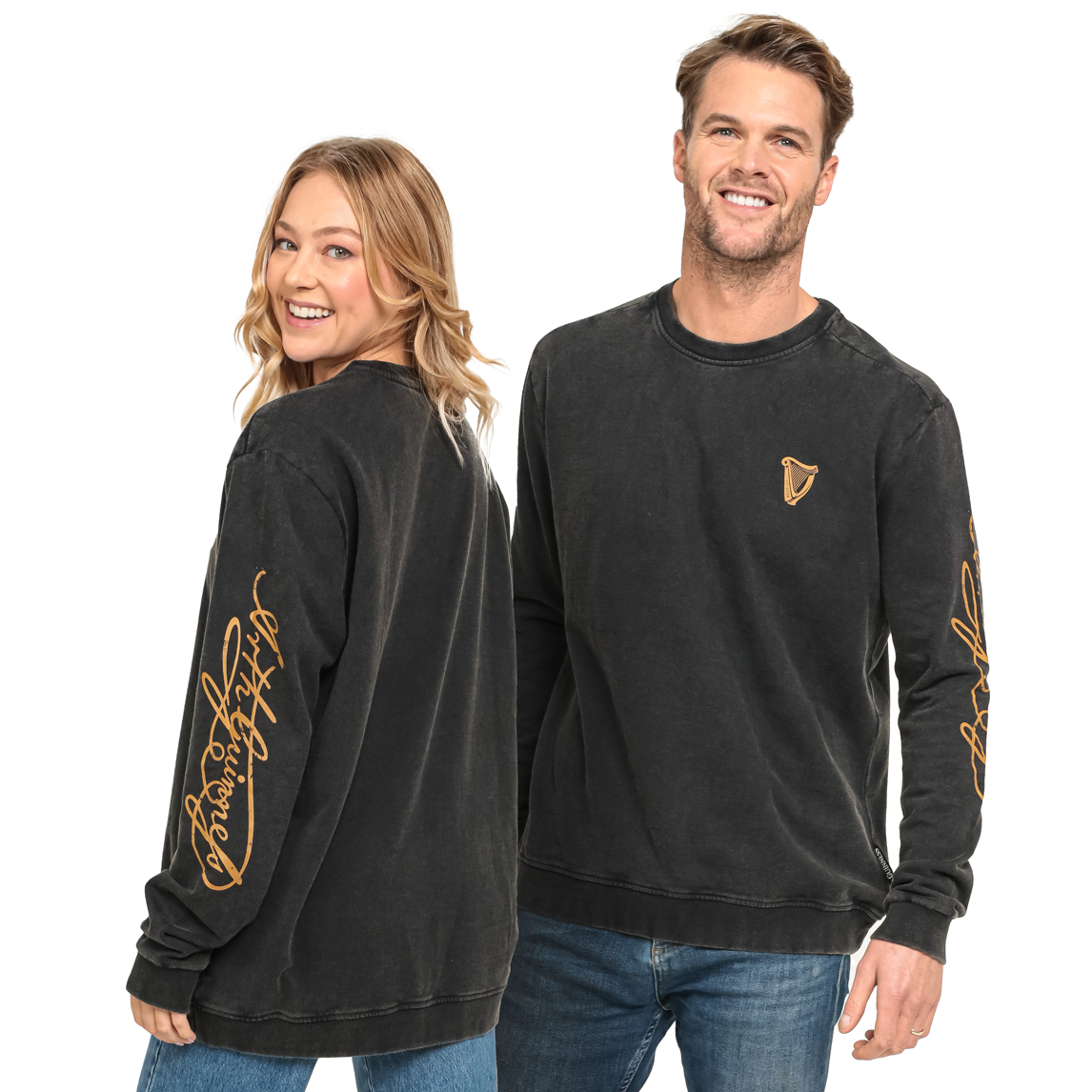 A man and a woman wear the black Guinness Gold Harp & Signature Distressed Sweatshirt featuring vintage-inspired gold harp and script graphics on the chest and sleeves.