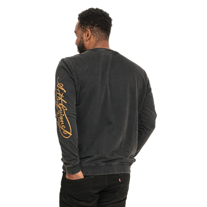 A person wearing a black Guinness Gold Harp & Signature Distressed Sweatshirt featuring a gold Guinness script logo printed vertically along the right sleeve.