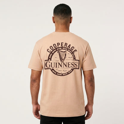 Man facing away in an oversized fit Guinness Cooperage Ivory Heavyweight Tee, large logo and “Cooperage” on the back. Brand: Guinness Webstore US.