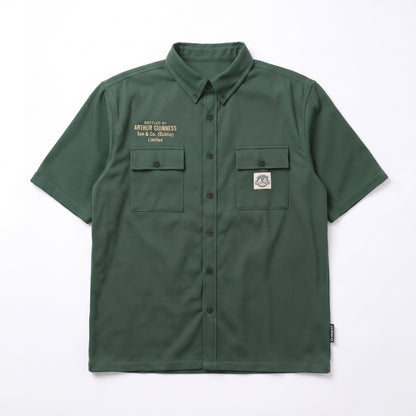 The Guinness Cooperage Work Shirt is a forest green, short-sleeve, heavyweight cotton button-up with two chest pockets, embroidered text left, and logo patch right.