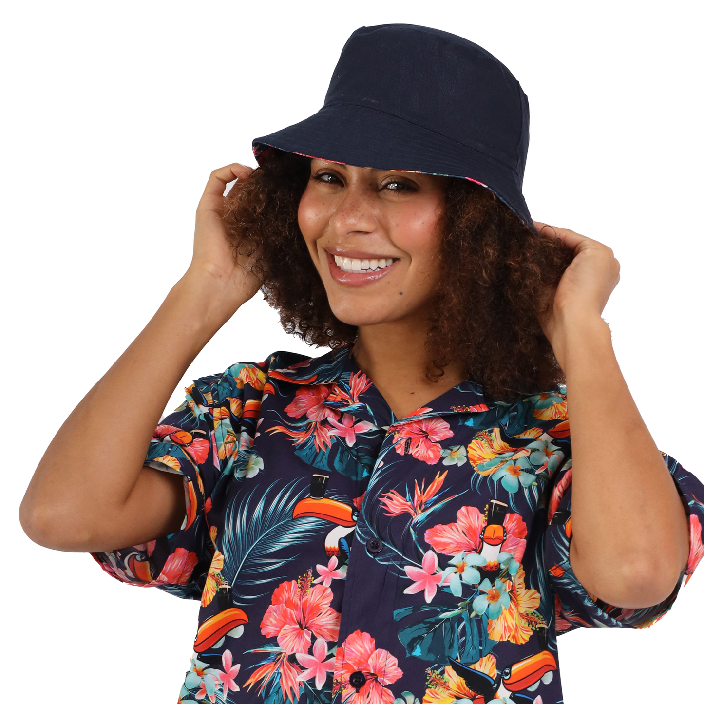 A person wearing a floral shirt and a stylish Guinness Webstore US Guinness Hawaiian Reversible Bucket Hat smiles while adjusting the hat with both hands.