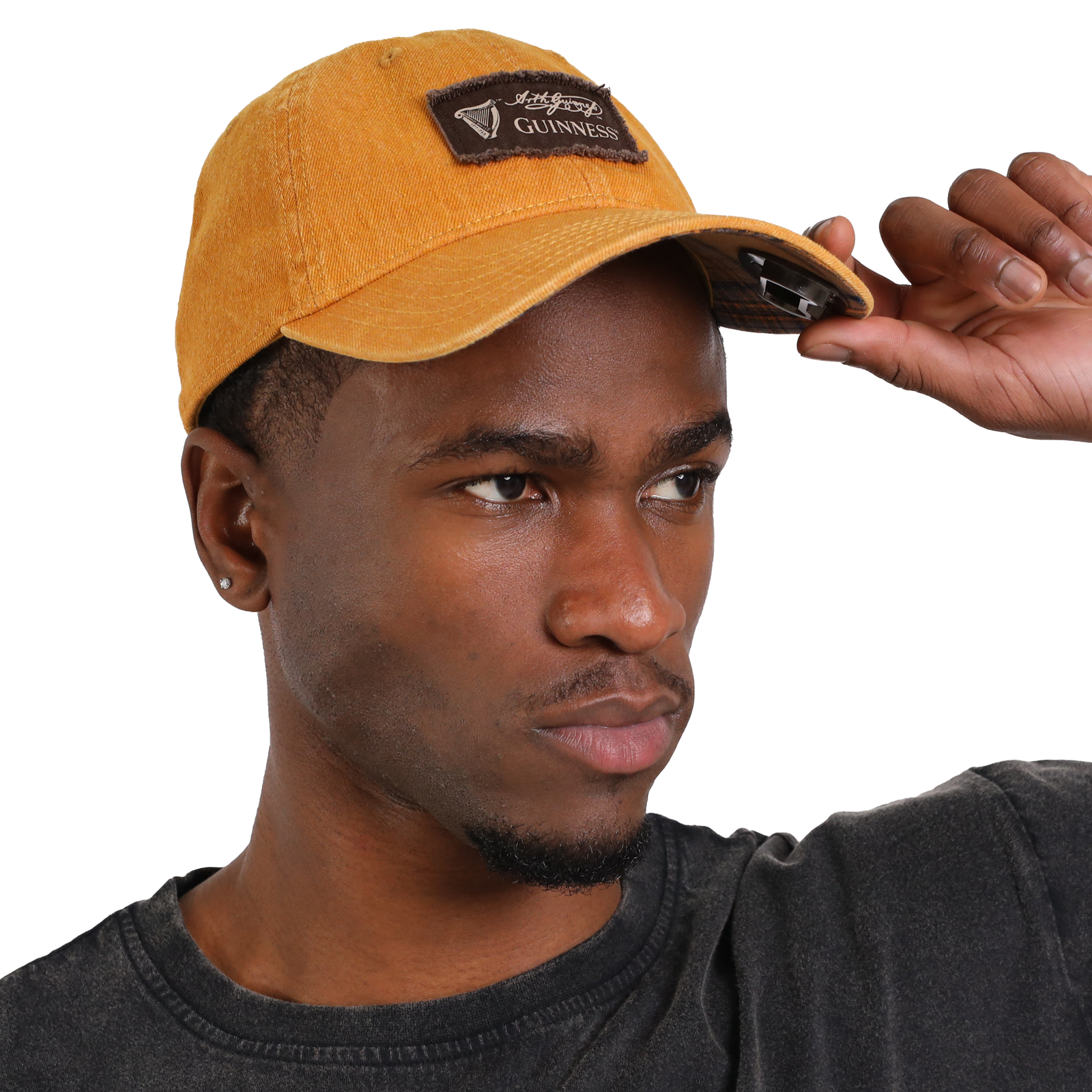 A man wearing a Guinness Mustard Bottle Opener Cap is adjusting the brim.