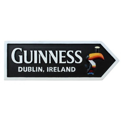 The Guinness Resin Magnet – Road Sign from Guinness Webstore US features "Guinness Dublin, Ireland" and a toucan with a pint on its beak, set on a black background with a white arrow border—an ideal Irish souvenir.