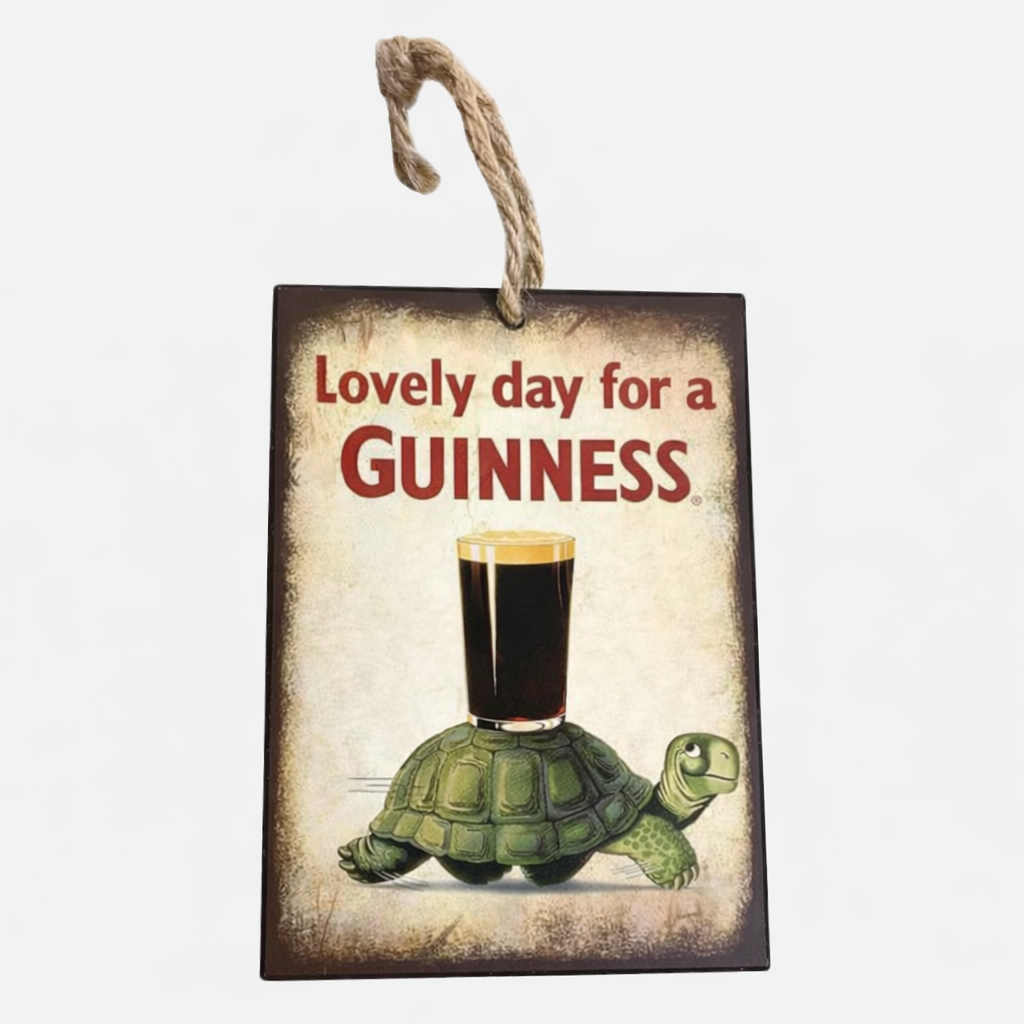 The Guinness US Tortoise Mini Metal Sign features "Lovely day for a GUINNESS" with a glass atop a turtle's shell, and hangs by a rope.