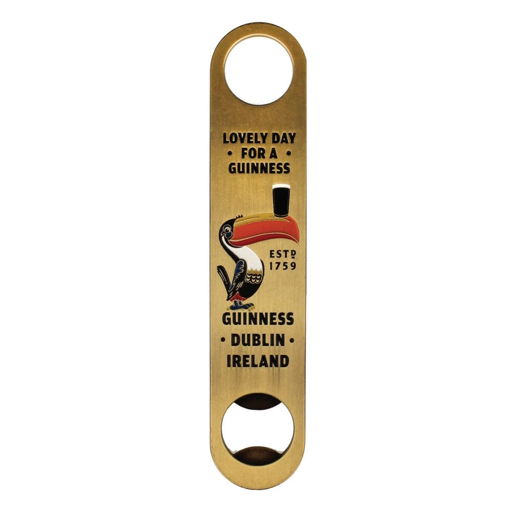 Gold-toned metal bar blade Guinness Gilroy Barman Bottle Opener featuring a Gilroy Toucan balancing a glass of stout with the text “Lovely day for a Guinness” and “Dublin, Ireland.”