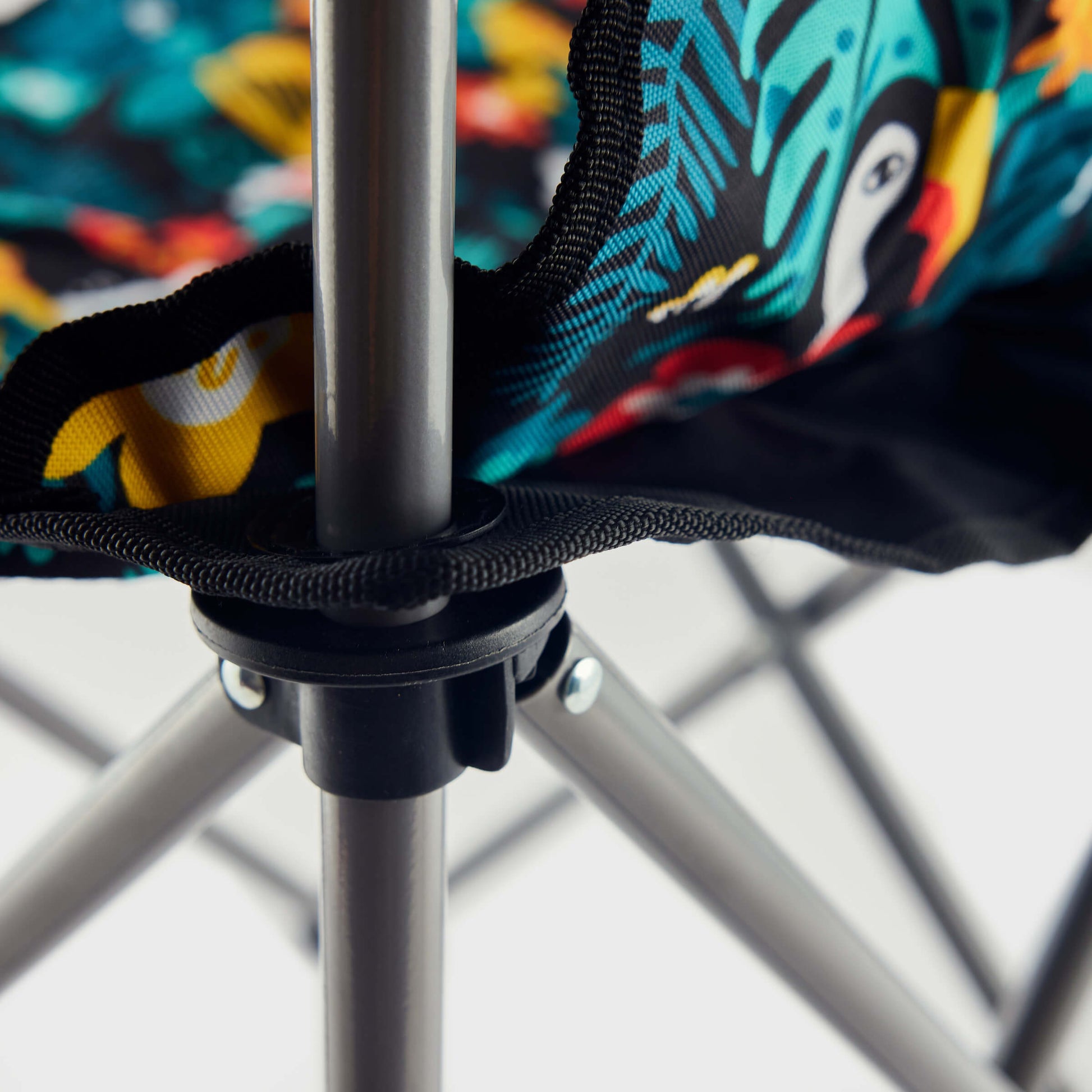 Close-up of the Guinness x Fatti Burke Hawaiian Camping Chair's metal frame and vibrant tropical print with toucan illustrations—ideal to pair with a colorful beach towel.