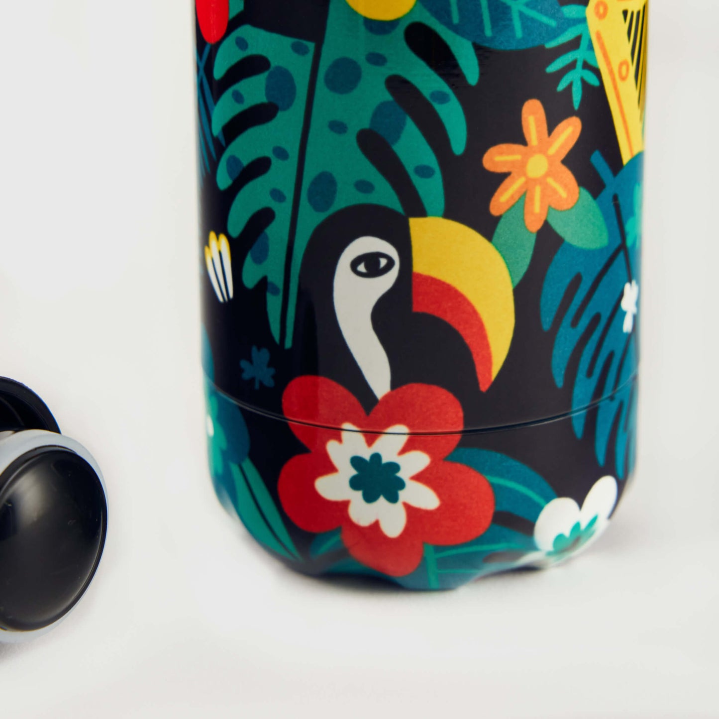 The Guinness x Fatti Burke Hawaiian Water Bottle by Guinness is BPA-free and reusable, featuring a colorful tropical design with a toucan, leaves, flowers, and a black lid visible on the left.