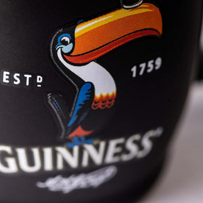 Close-up of a Guinness can featuring a colorful toucan logo with the text "ESTD 1759" and "GUINNESS," reminiscent of the design on the classic Guinness Toucan Black Mini Barrel Mug by Guinness Webstore US.