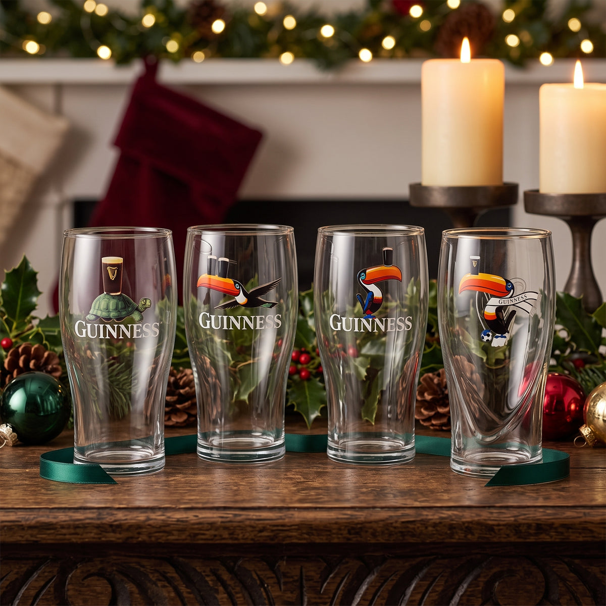 The Guinness Gilroy Christmas Glass Set from Guinness Webstore US is displayed on wood, a perfect festive gift among holiday décor and glowing candles.