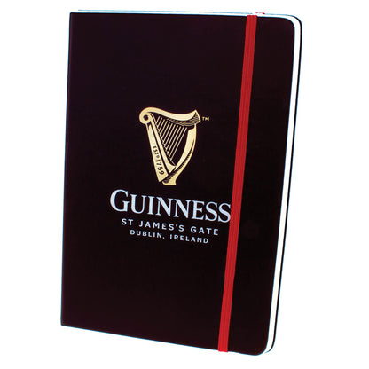 A black Guinness Harp Notebook with the Guinness US logo, including a harp and text reading "St James's Gate Dublin, Ireland." It features high-quality paper and a red elastic band for closure.