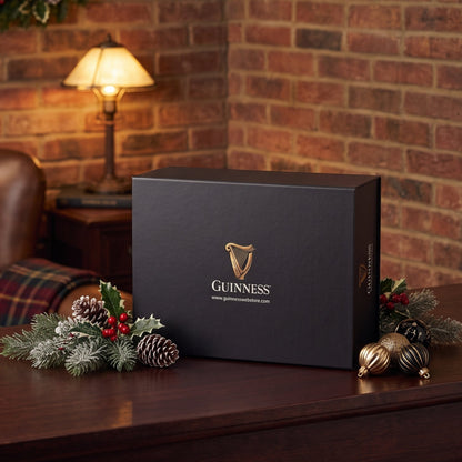 A Guinness Gift Box - Large sits on a wooden desk with Christmas decorations, making it a perfect Guinness gift or collector’s edition.