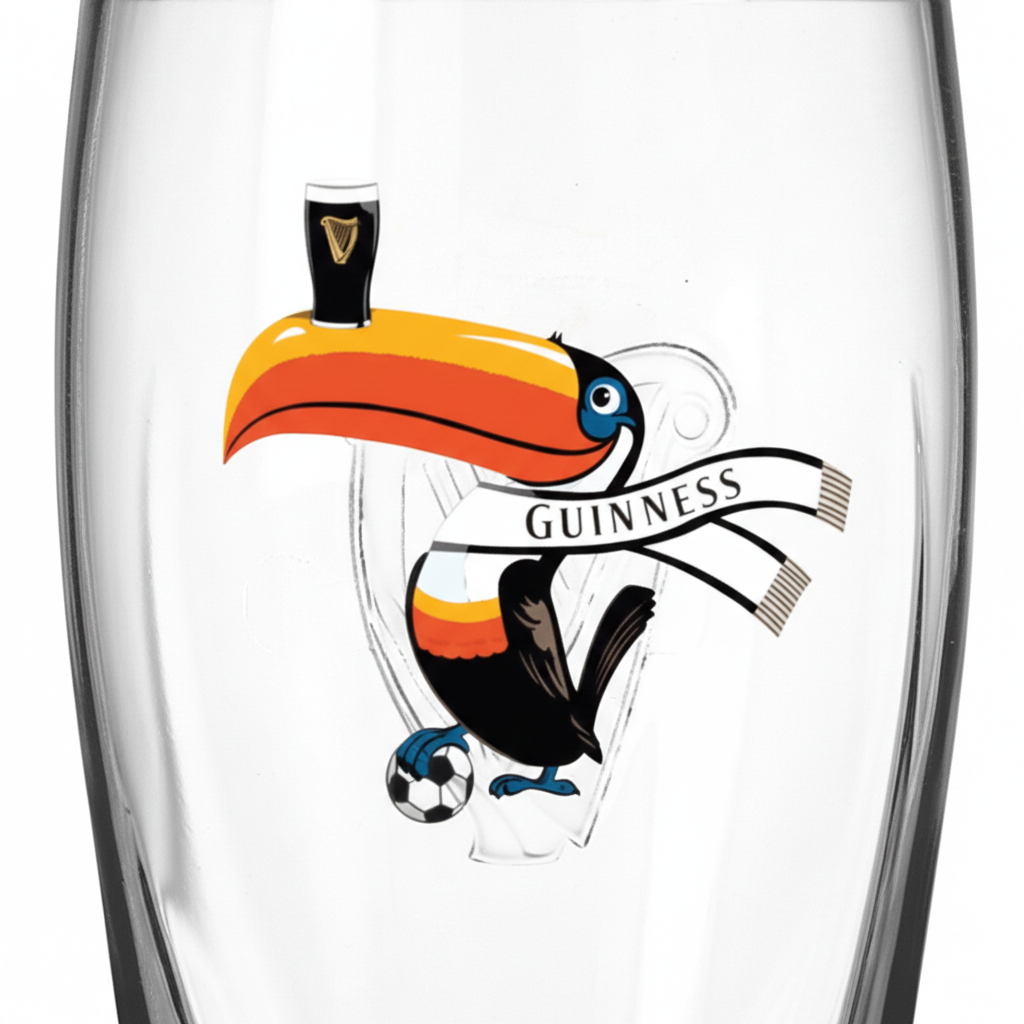 Raise a toast to the 2026 tournament with the Guinness Soccer Pint Glass – Special Edition from Guinness Webstore US, showcasing a vibrant toucan balancing a pint, holding a soccer ball, and clutching a "Guinness" banner.