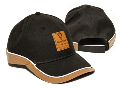 Two Guinness Black and Brown Caps from the Guinness Webstore US are displayed stylishly with white trim accents. One cap is positioned to showcase the front, featuring a "Guinness" logo patch representing the iconic Irish beer, while the other highlights the back with an adjustable strap.