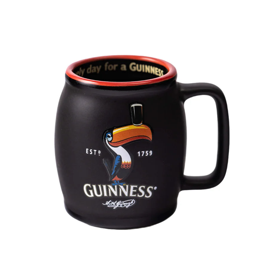 A Guinness Toucan Black Mini Barrel Mug from the Guinness Webstore US, featuring a black ceramic exterior with a red inner rim, and adorned with the iconic Guinness Toucan and the year 1759.