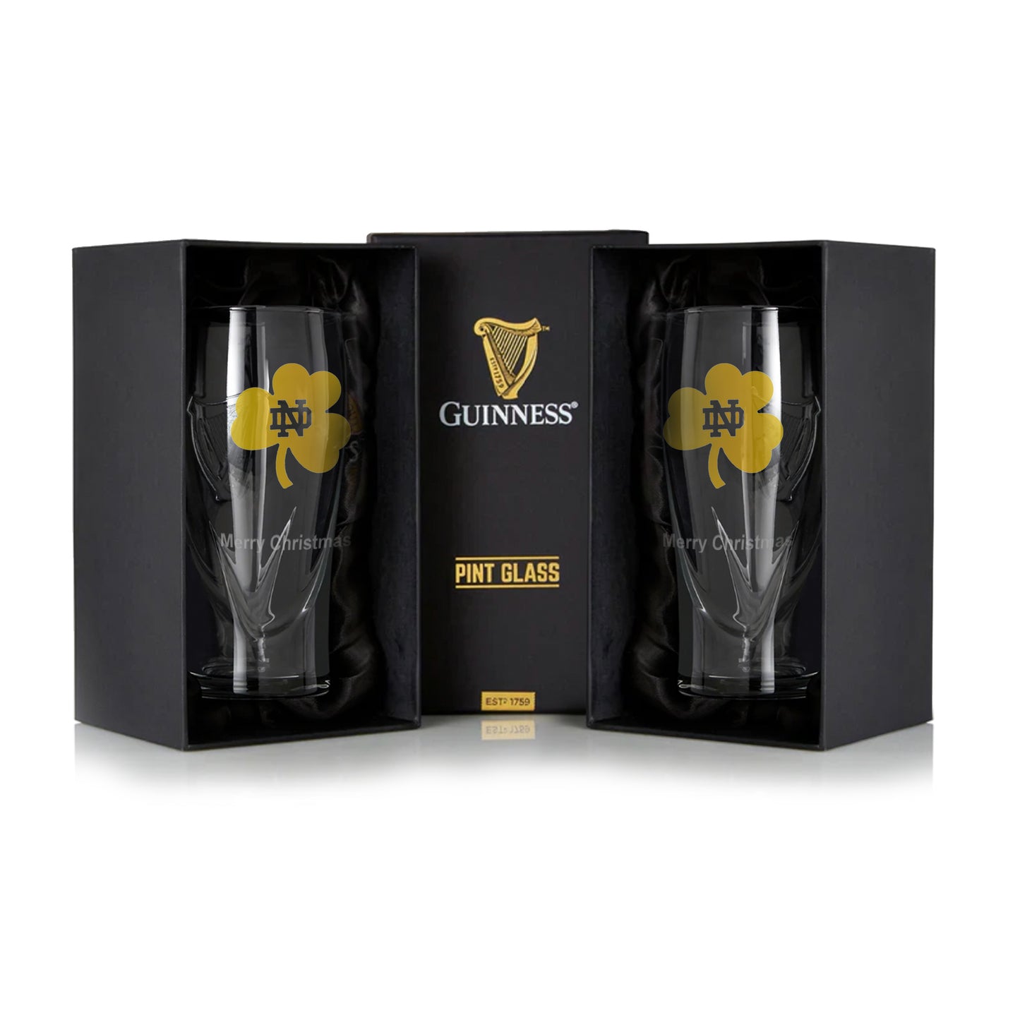 The Notre Dame Guinness Shamrock Twin Pack features two 16oz pint glasses in black boxes, each adorned with a gold shamrock and "Merry Christmas" text.