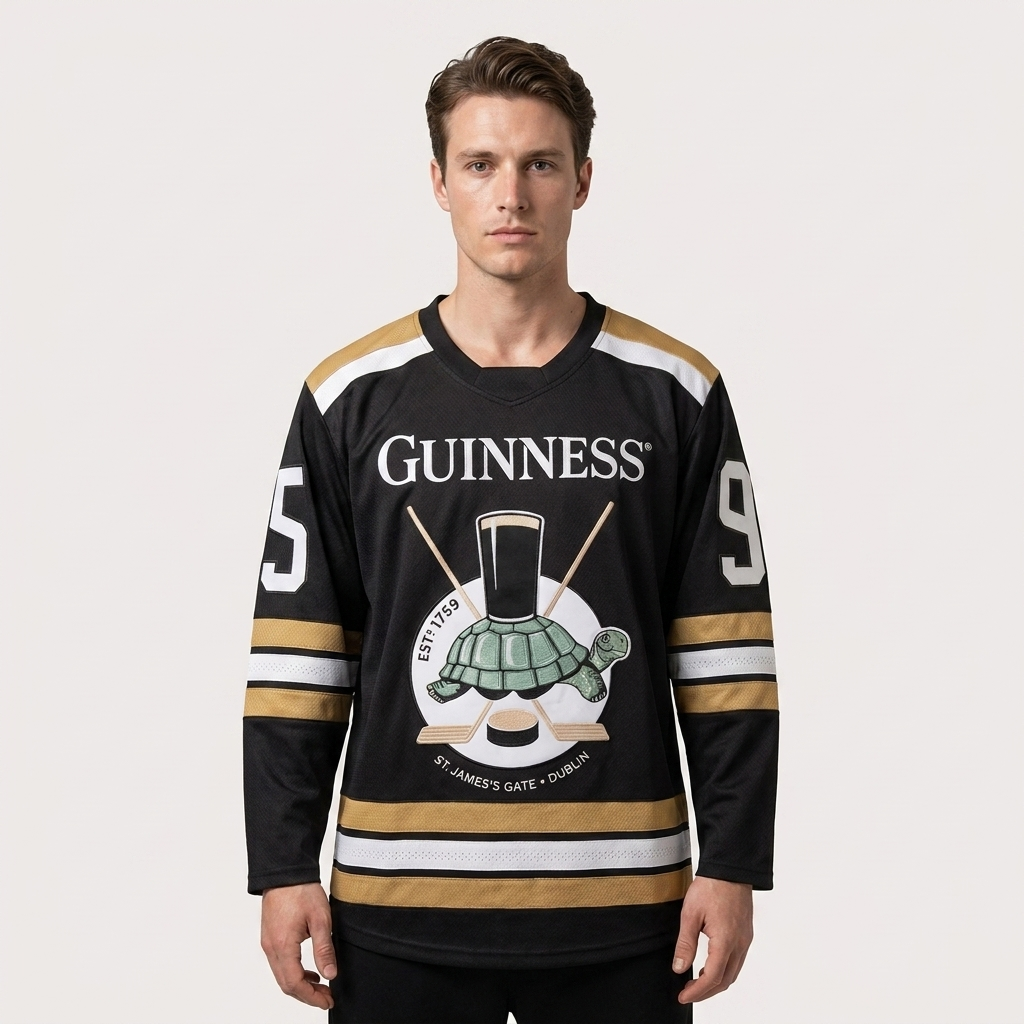 Wearing the Guinness Tortoise Hockey Jersey by Guinness Webstore US—an oversized piece crafted from recycled polyester, featuring the number 95, a turtle graphic, and crossed hockey sticks—a man stands against a plain background.