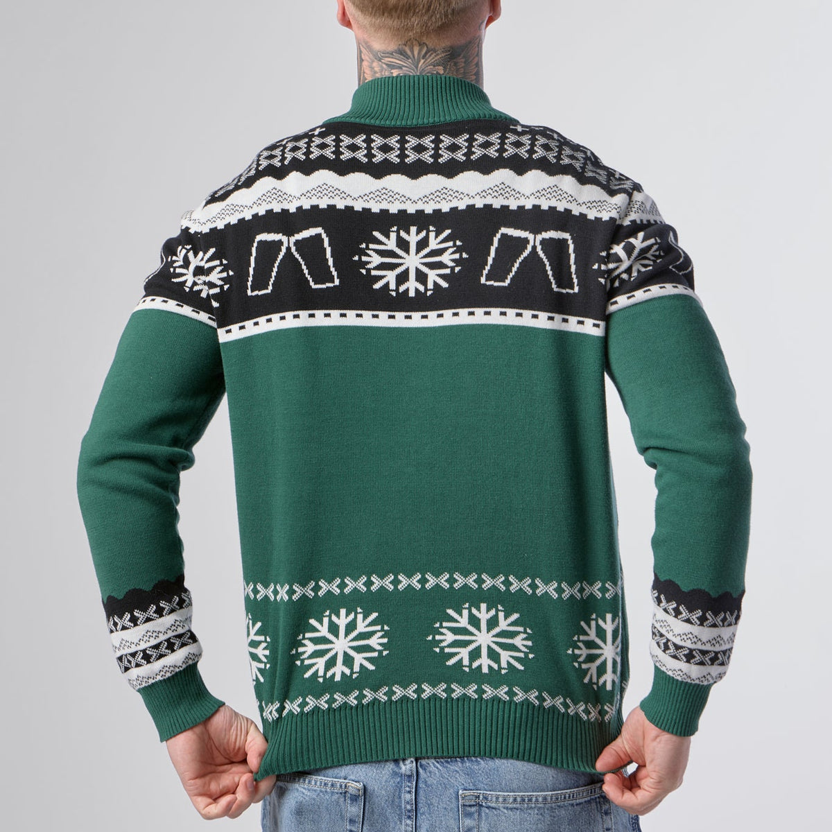 A person is seen from the back wearing the Guinness Holiday Quarter Zip Sweater in green, featuring black accents with snowflake and geometric patterns.