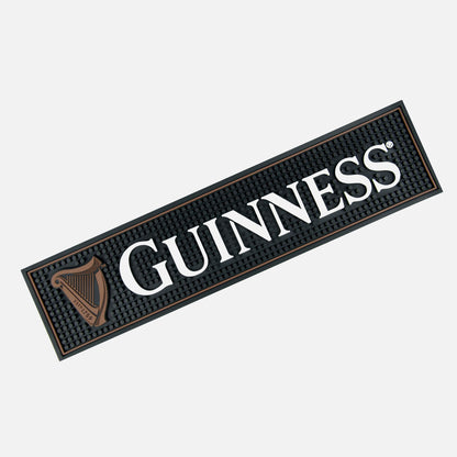 Add a touch of authenticity to your home bar with the Guinness Perfect Pour Bundle from Guinness Webstore US: a rectangular black textured bar mat featuring bold white “GUINNESS” text and the signature gold harp logo—ideal for displaying under any pint glass.