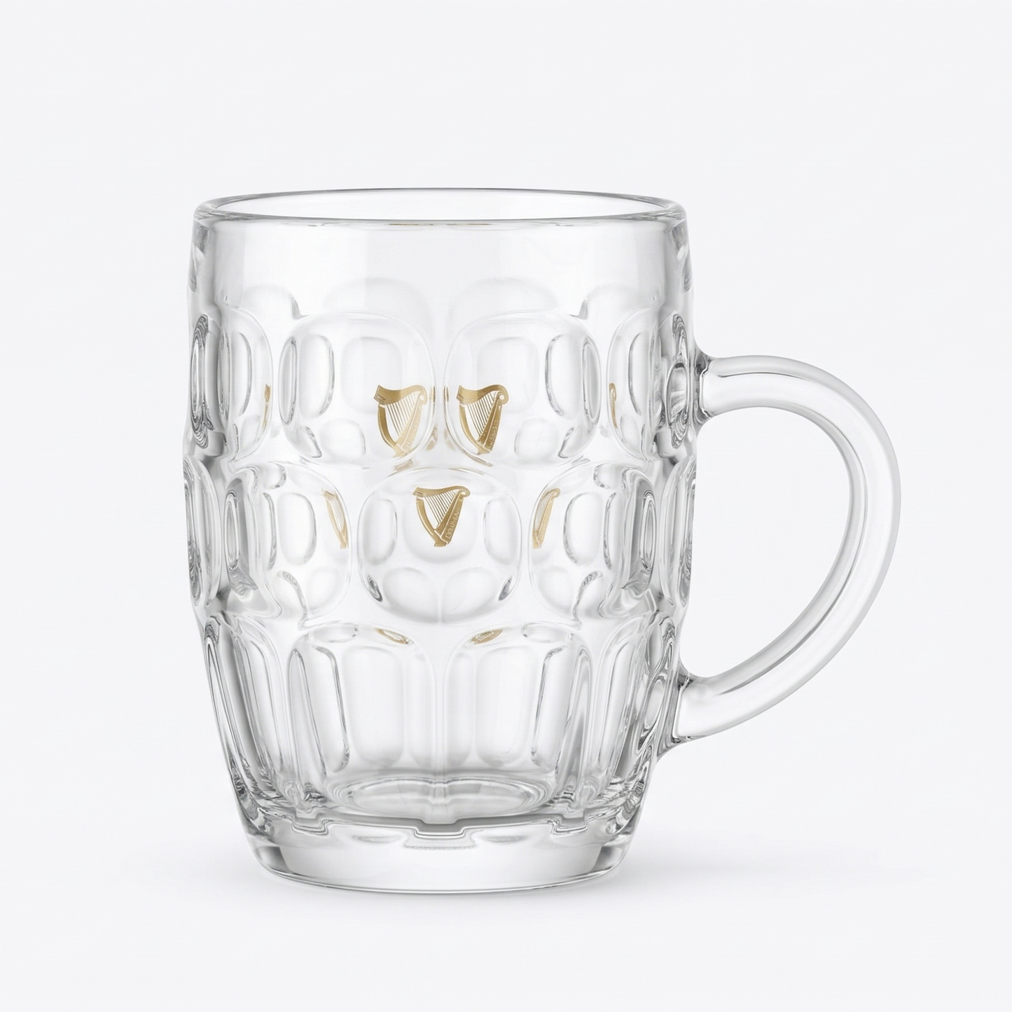 The Guinness Gold Harp Dimple Glass Mug – 20 oz Tankard from Guinness Webstore US features clear glass with a geometric texture, gold accents, and a handle—ideal as an Irish pub glass or for enjoying your favorite Guinness.