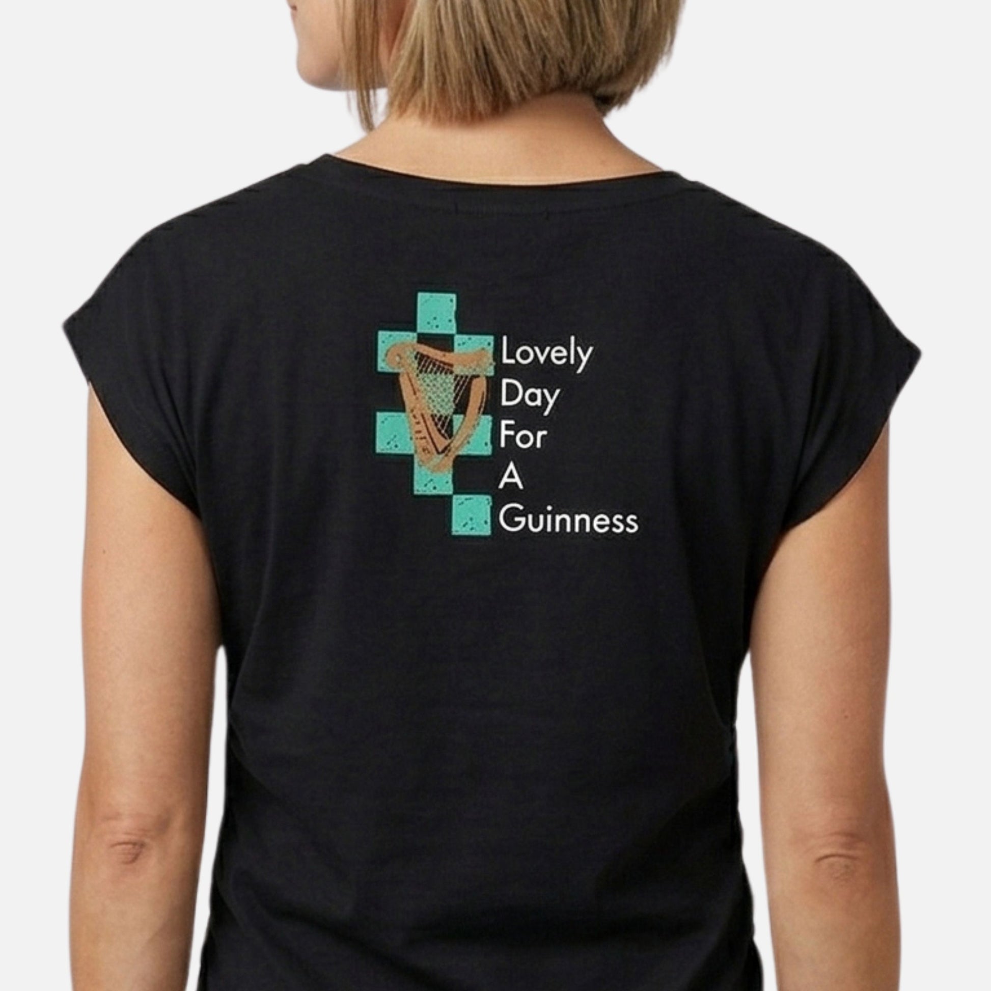 A person wearing the Guinness Toucan Ruched Ladies Black Tee from Guinness Webstore US, featuring a black design with text and graphics on the back.