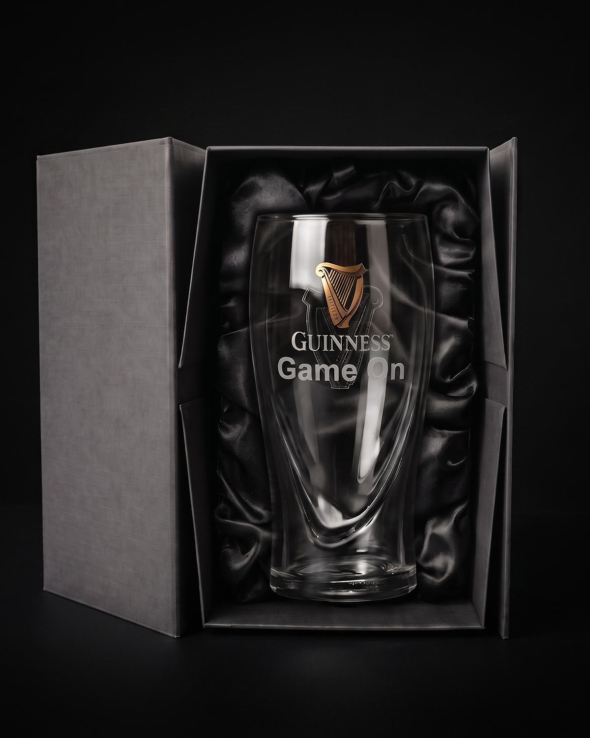 The Personalized Guinness Glass Gift Set from Guinness Webstore US sits upright in a black, satin-lined box—an ideal gift against a dark background.