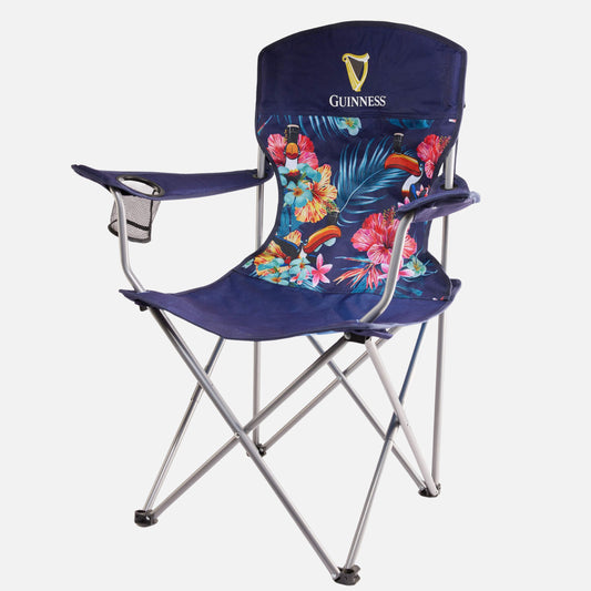 The Guinness Toucan Hawaiian Beach Chair from Guinness Webstore US features a blue foldable design, metal legs, floral seat pattern, Guinness logo on the backrest, and a mesh cup holder—perfect for beach comfort and style.