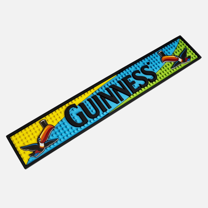 The Guinness Toucan PVC Bar Mat is displayed on a vibrant bar mat for your home bar.