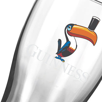 A clear glass from the Guinness Gilroy Christmas Glass Set features a festive toucan, making it a perfect Christmas gift from Guinness Webstore US.