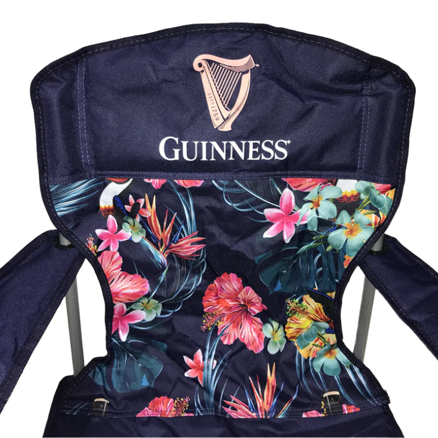 The Guinness Toucan Hawaiian Beach Chair features a dark blue floral design with the iconic logo, making it ideal for an outdoor setup when paired with the Guinness Toucan Hawaiian Cooler Bag.