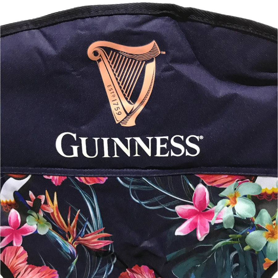 The Guinness Toucan Hawaiian Beach Chair features a dark floral pattern with red and pink flowers. The top showcases the iconic Guinness logo with a harp, adding Irish charm to your outings. Available at the Guinness Webstore US.