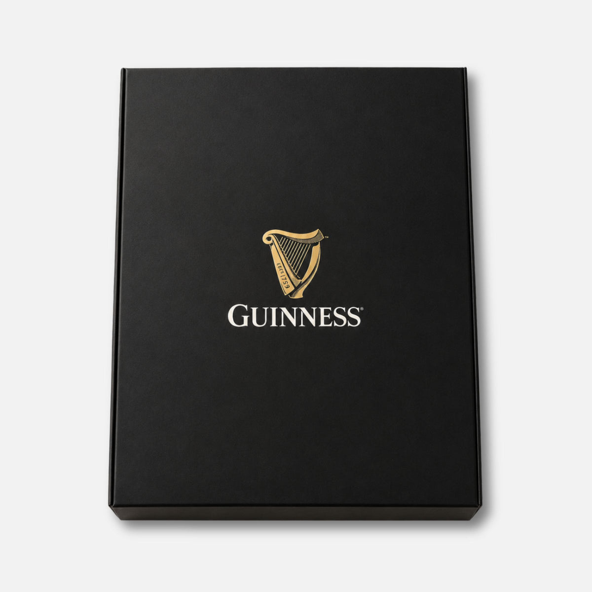 A black rectangular Guinness gift box for a Guinness Unisex 2-Piece Pajama Set – Green, featuring a gold harp logo and the word “Guinness” printed in the center.