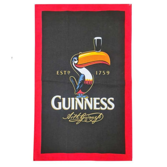 Add quirky flair to your kitchen with the Guinness US Toucan Tea Towel, featuring a black design, red border, colorful toucan with a pint of Guinness, plus “ESTD 1759,” “GUINNESS,” and a gold signature.