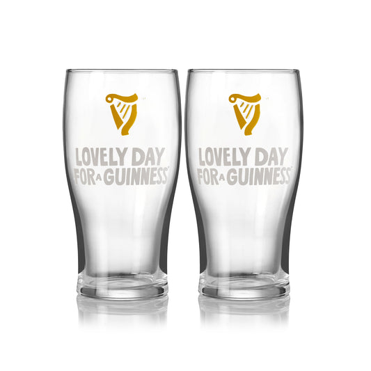 The Guinness Seb Curi Lovely Day Pint Glass 2 Pack from Guinness Webstore US features two collector’s edition pint glasses with the harp logo and "Lovely Day for a Guinness," inspired by Sebastian Curi, shown side by side on a white background.
