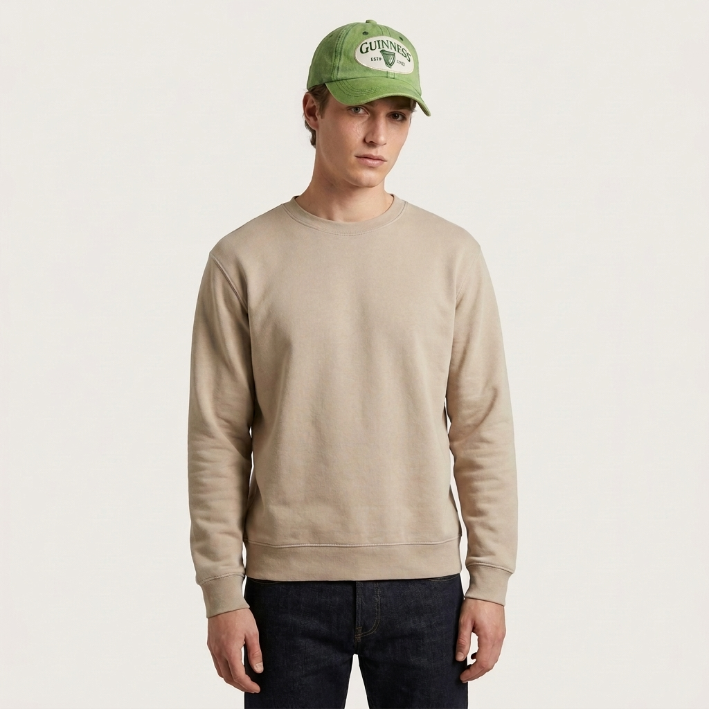 A man wearing a Guinness Green Distressed Baseball Cap and a tan crewneck sweatshirt.