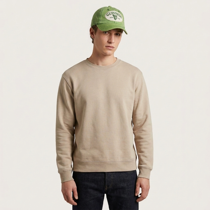 A man wearing a Guinness Green Distressed Baseball Cap and a tan crewneck sweatshirt.